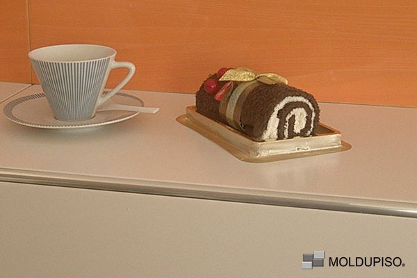 Tira esquinera de aluminio estándar en desayunador con un café y un pastel con pared anaranjada con moldura de aluminio