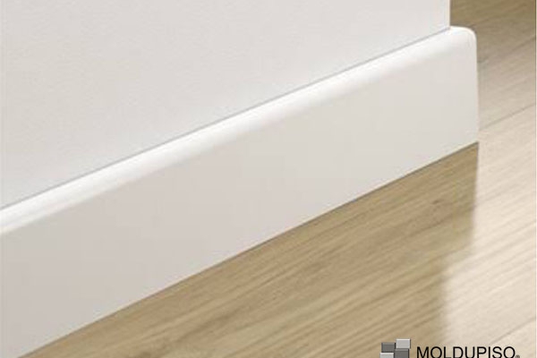 Zoclo de aluminio blanco en pared blanca con suelo de madera con moldura de aluminio