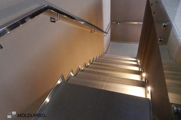 Zoclo de aluminio en escalera color gris iluminada en interiores con moldura de aluminio